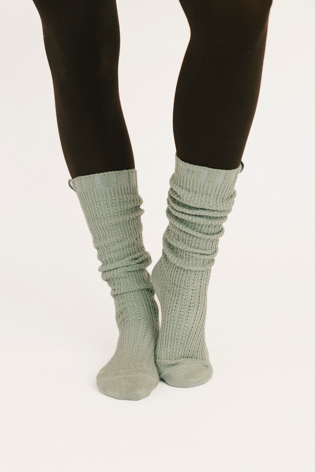 Light gray ribbed socks worn with black leggings on a white background