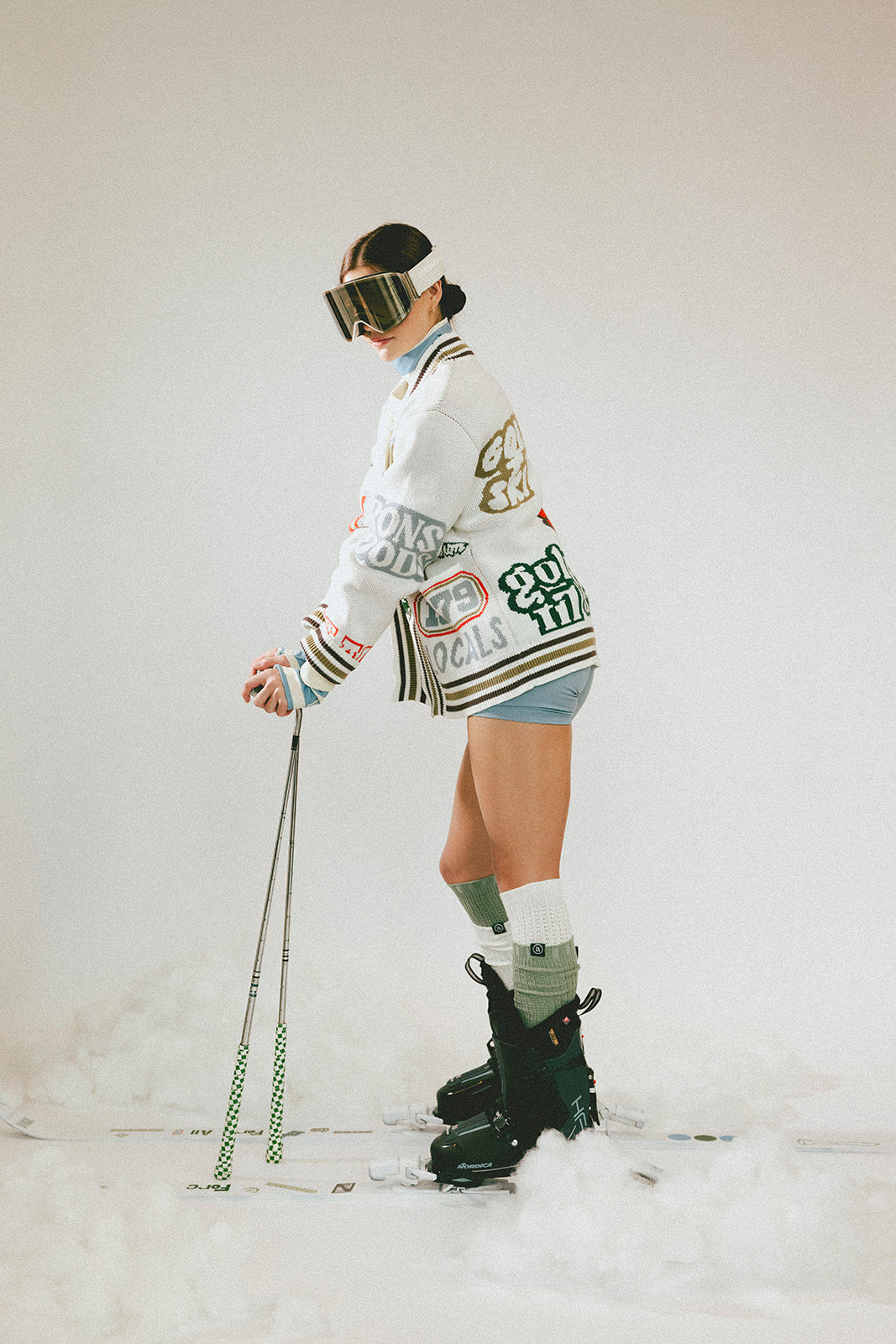 Person in winter gear with skis and poles on a white background