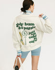 Person wearing a white sweatshirt with text and graphics, holding ski goggles.