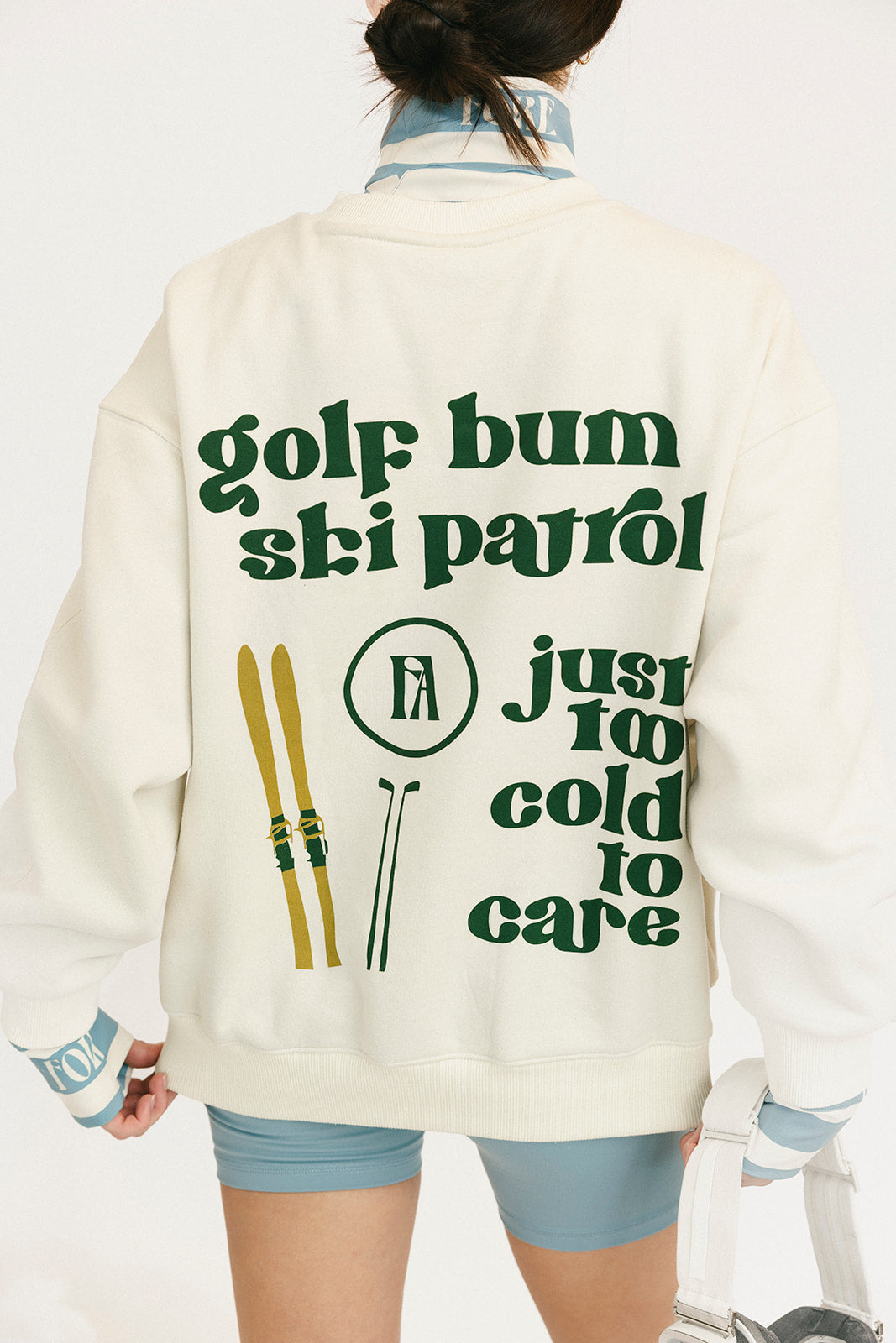 Person wearing a jacket with 'golf bum ski patrol' text and graphics on the back.