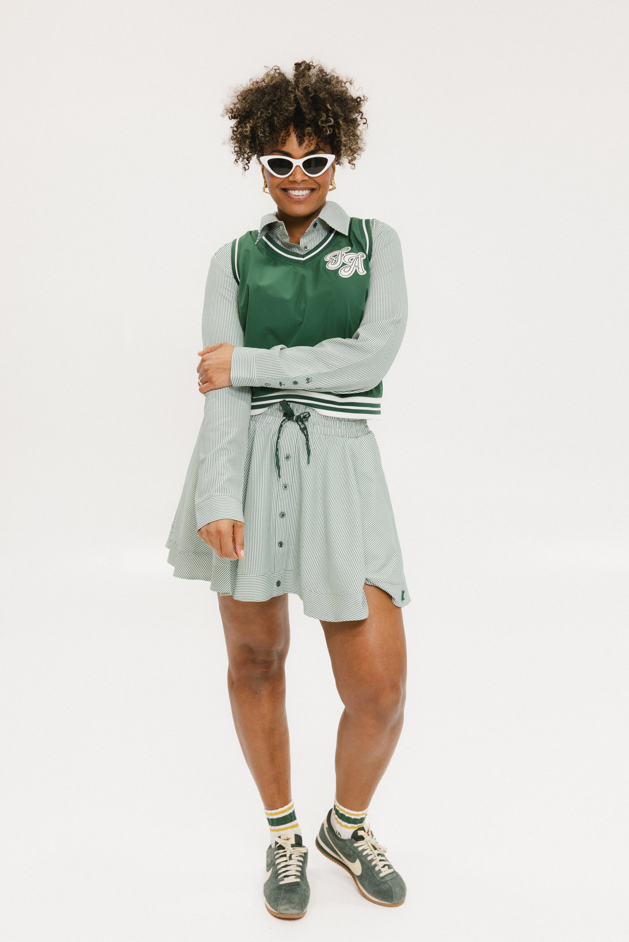 Person wearing a green felix vest with a victoria button up and patty skirt with a collar on a white background