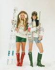 Two people in winter clothing with skis and ski poles on a white background