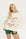 Woman wearing a white sweatshirt with red text and green shorts on a white background
