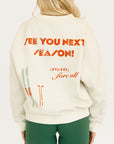 Woman wearing a white sweatshirt with red text and green shorts on a white background