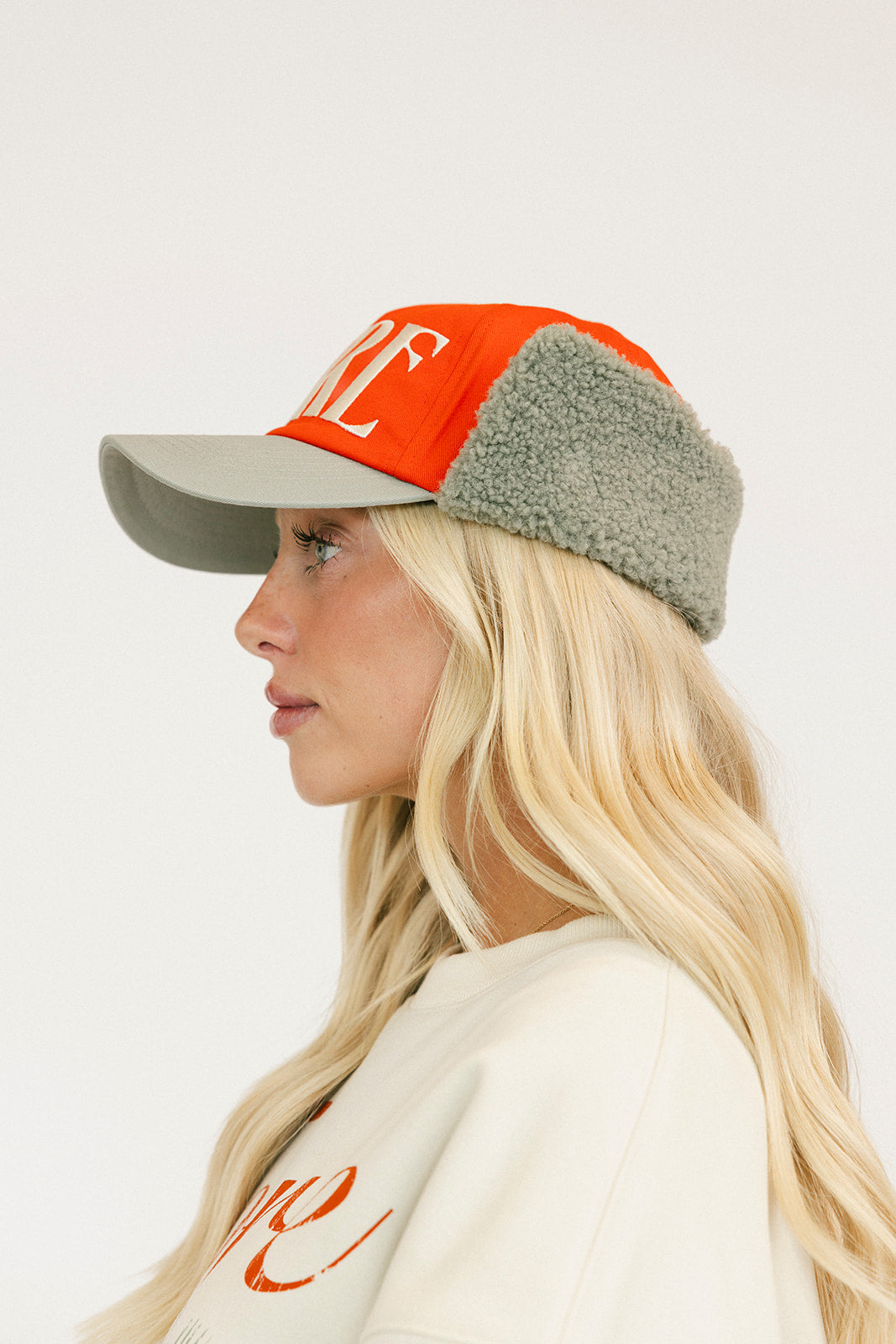 Person wearing an red cap and a white sweatshirt with red text on a light background