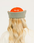 Person wearing an red cap and a white sweatshirt with red text on a light background