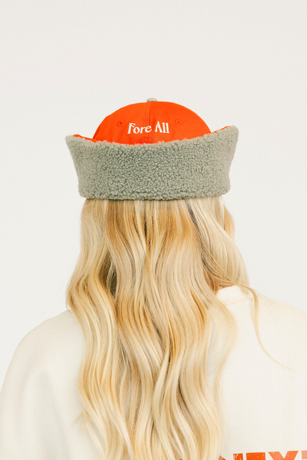 Person wearing an red cap and a white sweatshirt with red text on a light background