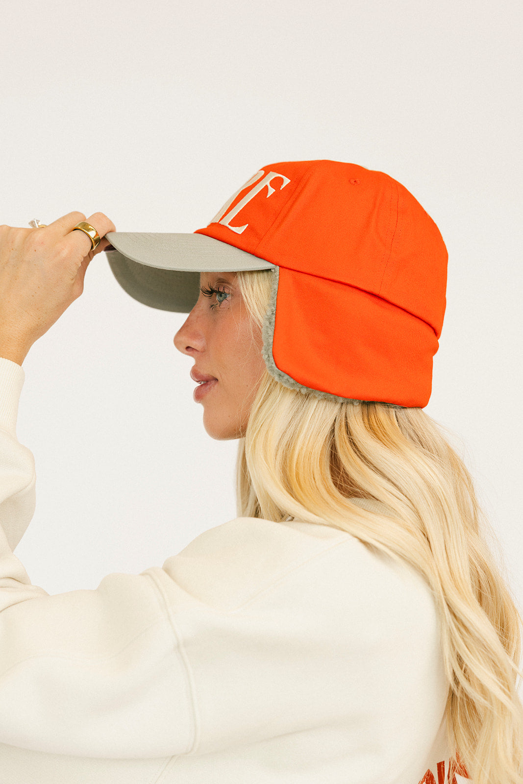 Person wearing a red cap and a white sweatshirt with red text on a light background