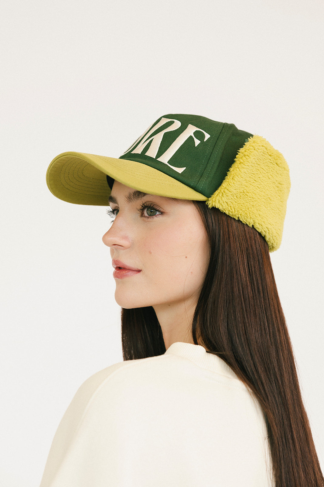 Person wearing a green and avocado cap with 'FORE' on a white background