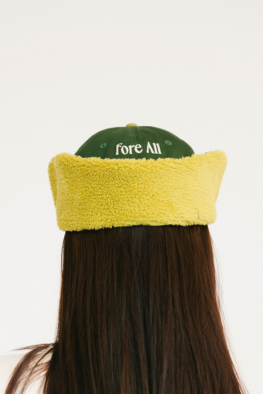 Person wearing a green and avocado cap with &#39;FORE&#39; on a white background