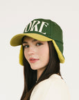 Person wearing a green and avocado cap with 'FORE' on a white background