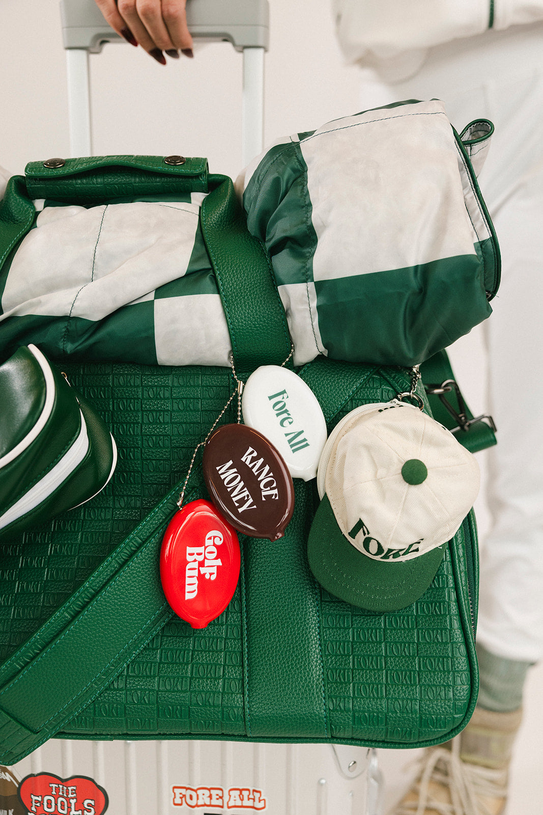 Green bag with various branded keychains on a white background