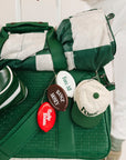 Green bag with various branded keychains on a white background