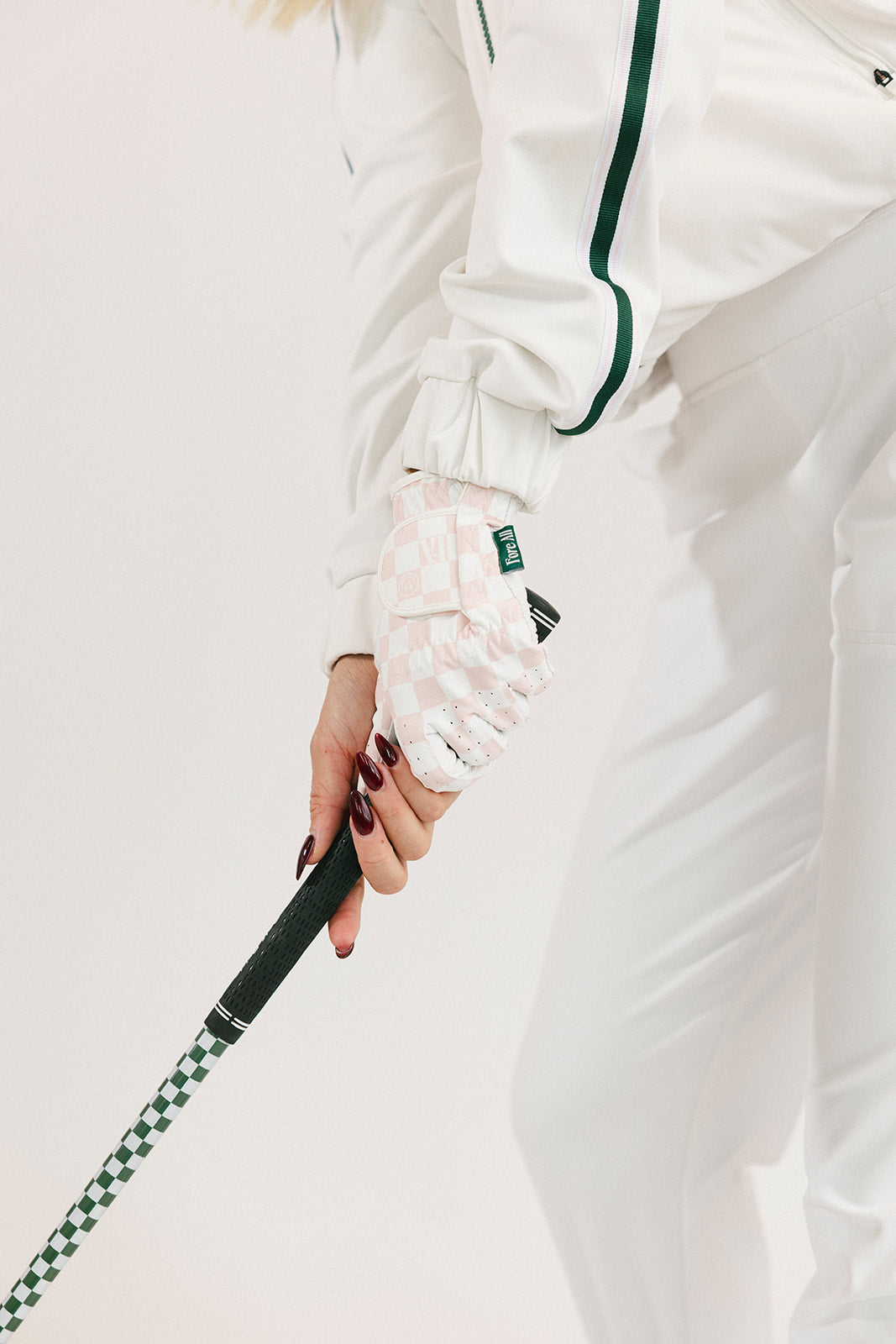 Person wearing a white outfit with green accents, holding a golf club.