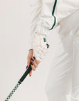 Person wearing a white outfit with green accents, holding a golf club.
