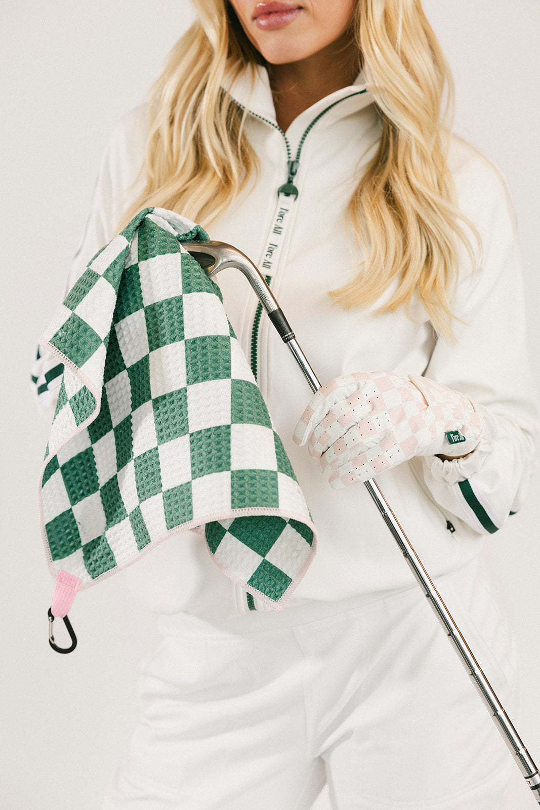 Person holding a golf club with a green and white checkered towel