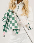 Person holding a golf club with a green and white checkered towel
