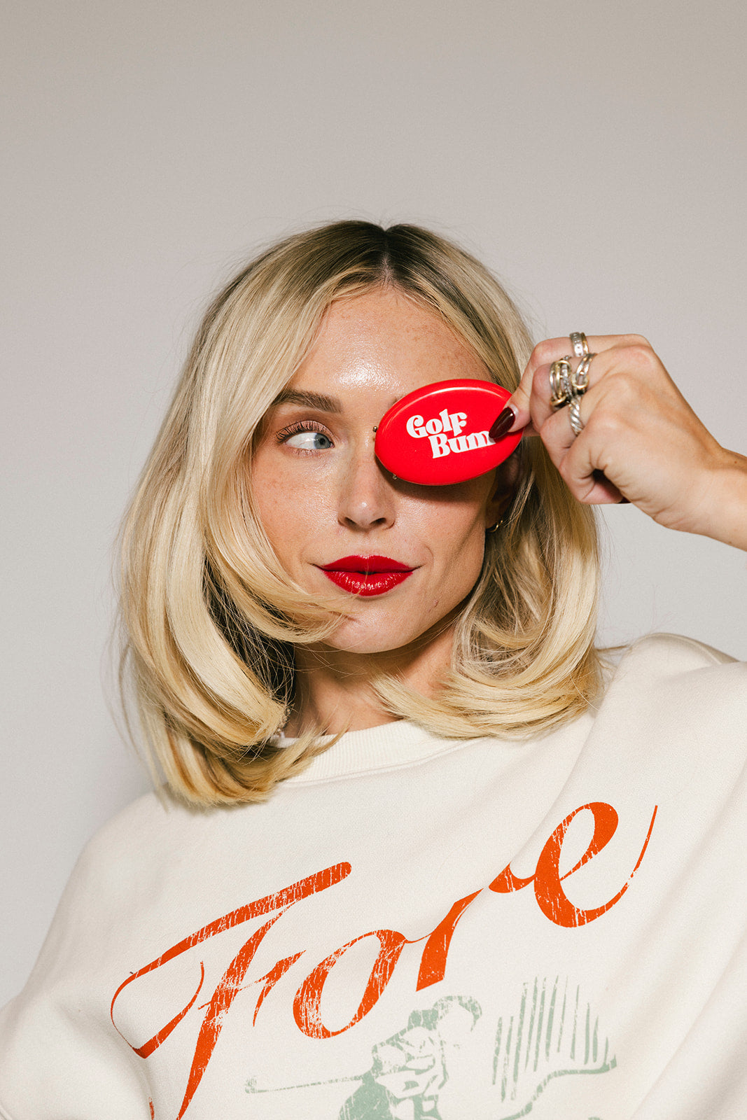 Person holding a red 'Cola Bum' product over one eye against a plain background