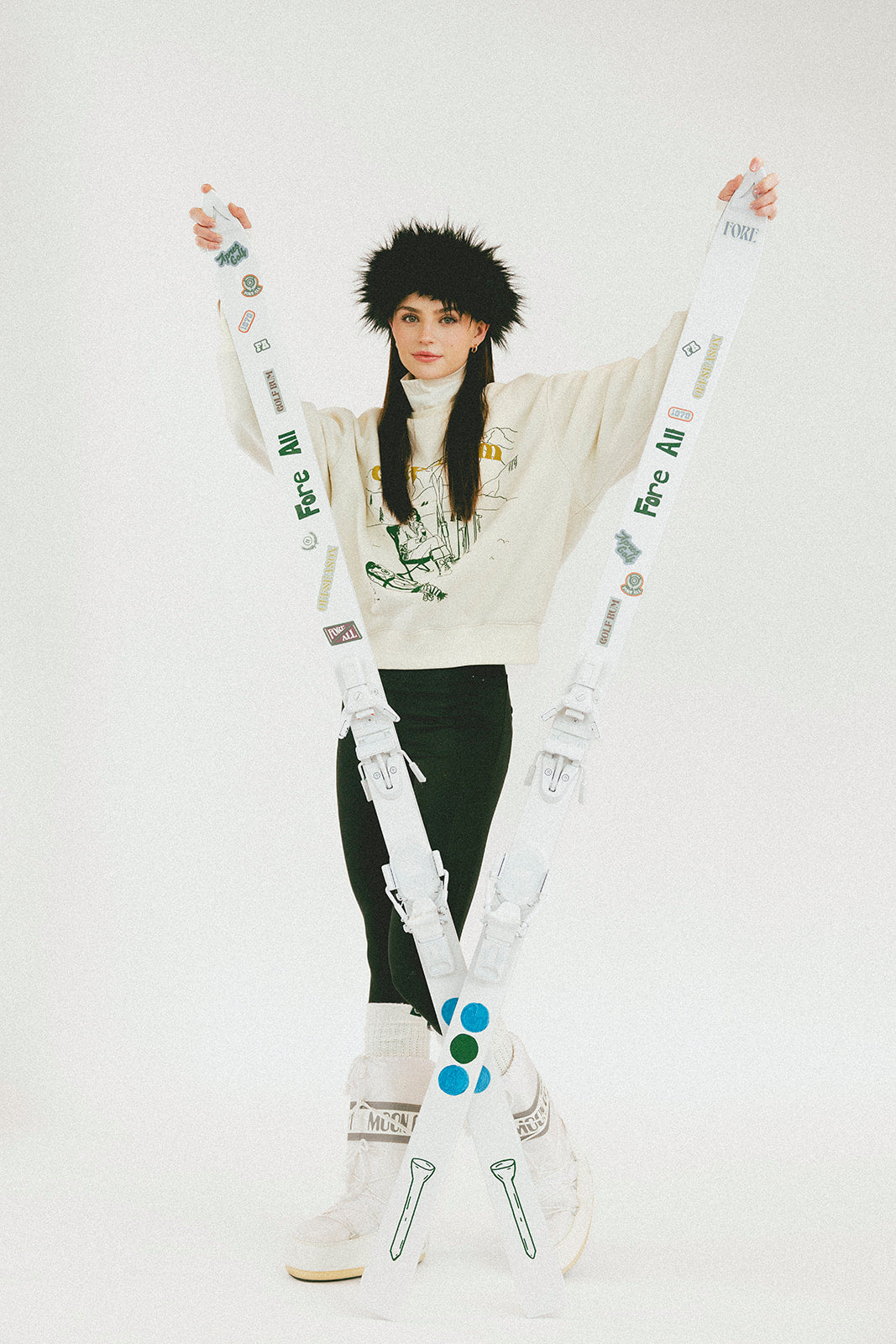 Person wearing a white sweater with text and black pants, standing against a white background.