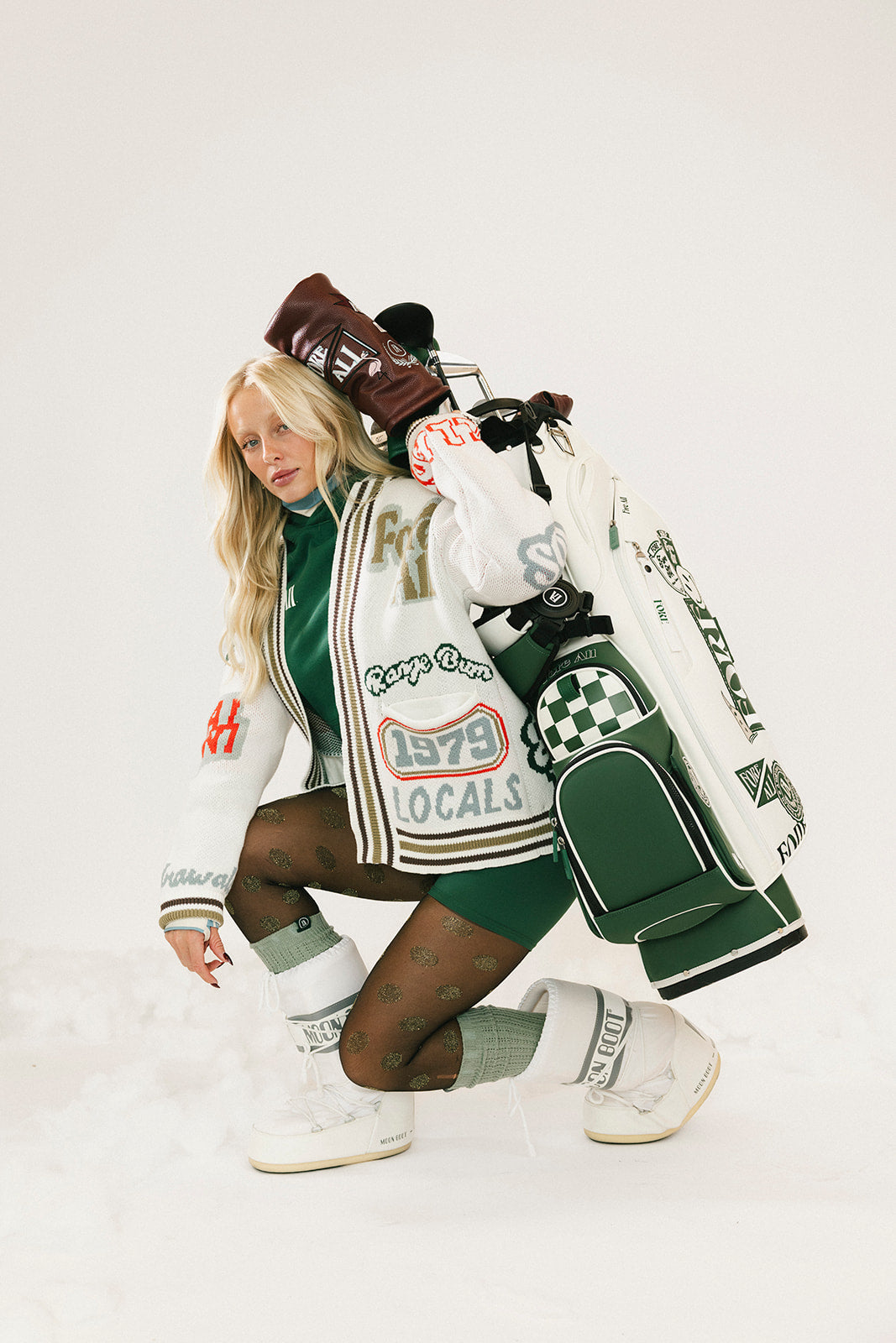 Person wearing a stylish outfit with a jacket, hat, and bag on a white background