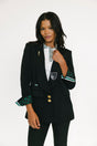 Woman wearing a black blazer with green and white accents on a white background
