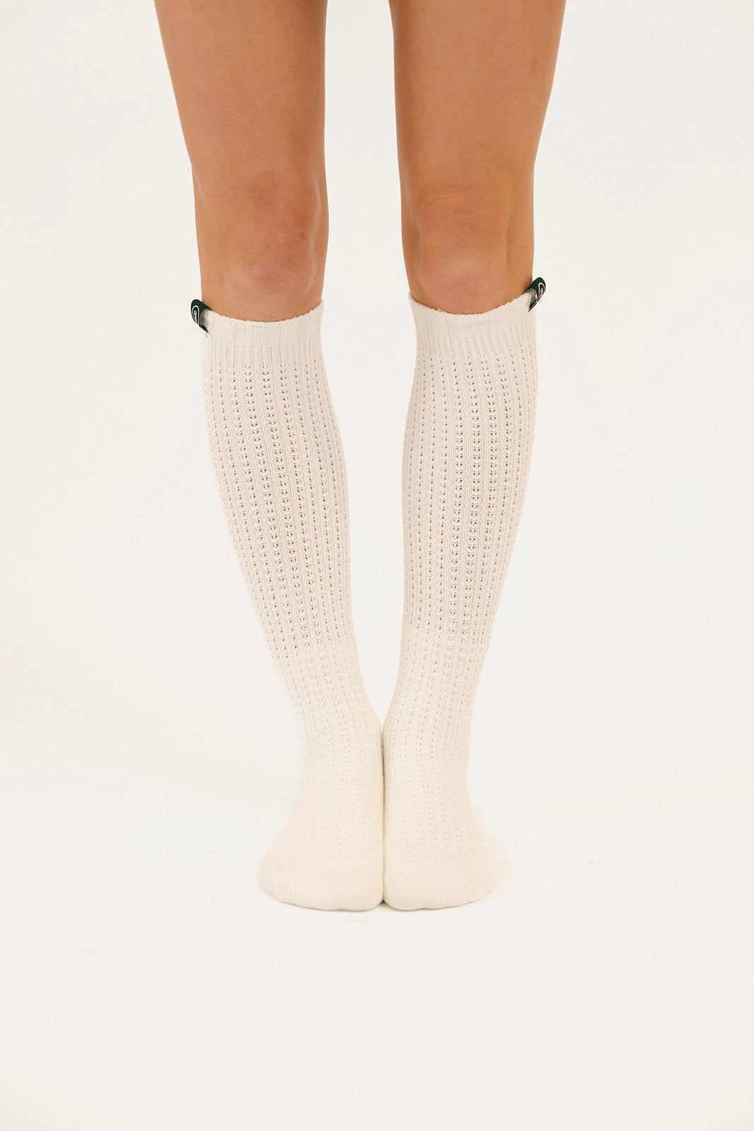 White knee-high socks worn by a person on a light beige background