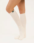 White knee-high socks worn by a person on a plain background
