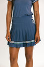 Person wearing a blue pleated skirt with white stripes on a plain background