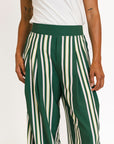 Person wearing green and white striped pants with a white top on a white background