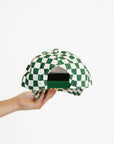 Green and white checkered cap held by a hand on a white background