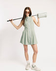 Woman in a light green dress holding a golf club on a white background