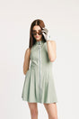 Woman wearing a light green sleeveless dress with a white background
