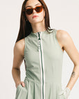 Woman wearing a light green sleeveless dress with a zipper on a white background