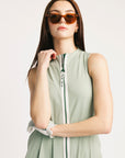 Woman wearing a light green sleeveless dress with a zipper on a white background