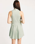 Woman wearing a light green sleeveless dress against a white background