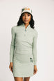Woman wearing a light green long-sleeve dress and cap on a white background