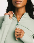 Person wearing a light green jacket with a close-up of the zipper area.