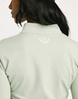 Light green long-sleeve shirt with a logo on the chest against a white background