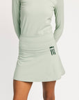 Light green athletic outfit with skirt and long-sleeve top on a white background