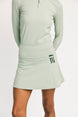 Light green athletic outfit with skirt and long-sleeve top on a white background