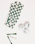 Green and white checkered golf glove with golf balls and tees on a white background
