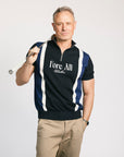 A man wearing a navy zip sweater with vertical white stripes and the text 'Fore All' on the chest, paired with beige pants.