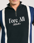 A man wearing a navy zip sweater with vertical white stripes and the text 'Fore All' on the chest, paired with beige pants.