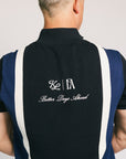 A man wearing a navy zip sweater with vertical white stripes and the text 'Fore All' on the chest, paired with beige pants.