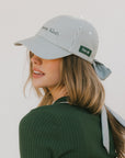 Woman wearing a striped baseball cap and green sweater with white stripes on a plain background
