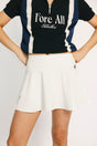 A person wearing an off-white high-waisted skirt with built-in shorts, a black and blue top with the text 'Fore All' on it, and a metal ring detail at the waist.