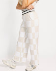 Person wearing a white and sand checkered Kennedy outfit with a plain background