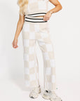 Person wearing a white and sand checkered Kennedy outfit with a plain background