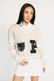 Woman wearing a cream sweater with black lettering and white skirt on a white background