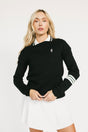 Woman wearing a black dorothy sweater with a white collar and white skirt on a light background
